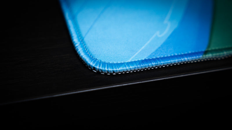 Close-up of the blue stitched edge on ItzOutlaw's Glorious Victory gaming desk mat
