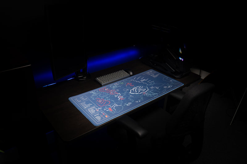 Wide angled view of the Jaush strategy map deskmat on a dark desk with blue lighting, monitors, and a PC.