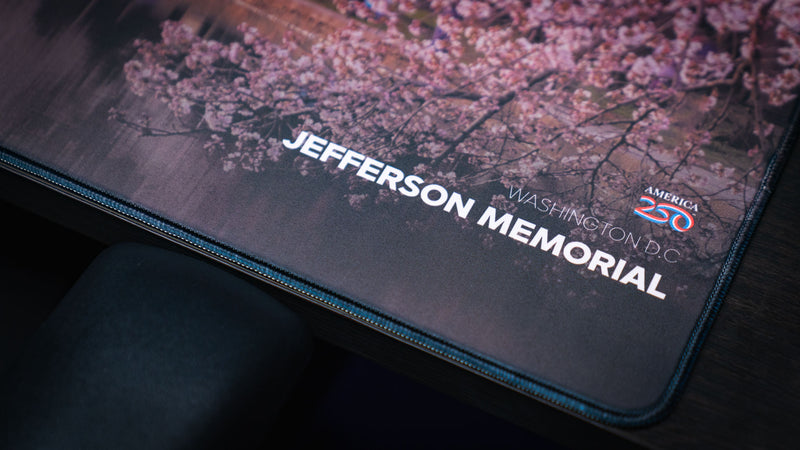 efferson Memorial deskmat corner detail featuring Washington D.C. text, America 250 branding, soft cherry blossom artwork, and stitched edging.