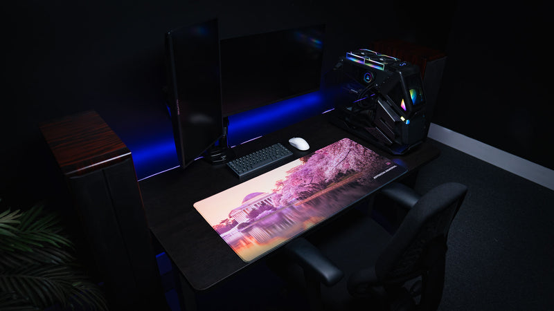 Overhead view of the Jefferson Memorial deskmat featuring pink cherry blossoms, reflective water, and monument artwork in a dark gaming setup.