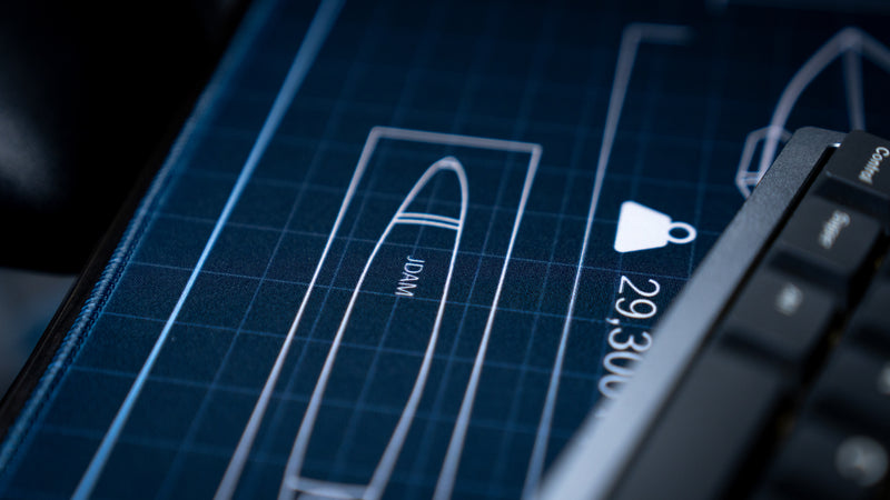 Close-up of the JDAM ordnance blueprint on the Jimarkus F35 Schematic deskmat beside a mechanical keyboard, highlighting technical aircraft design details.