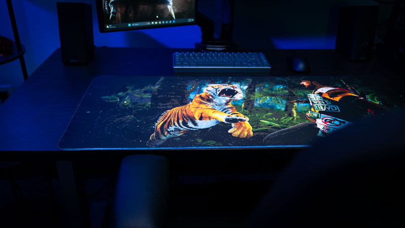 Official Rust Jungle Ambush deskmat displayed on a gaming desk, featuring a tiger attack scene and immersive jungle artwork.