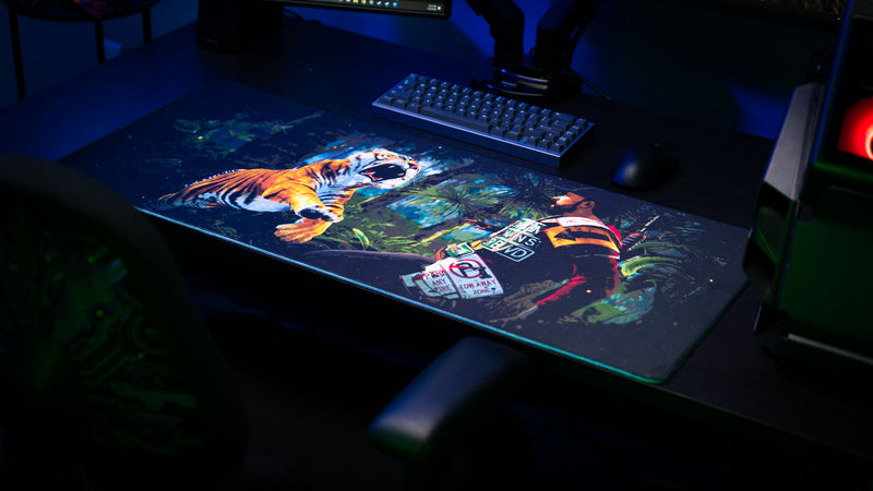 Official Rust Jungle Ambush deskmat displayed on a gaming desk, featuring a tiger ambush scene in a dense jungle environment.