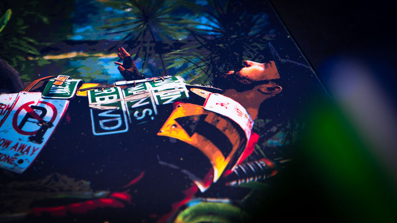 Close-up of a Rust survivor lying in dense jungle foliage on the official Jungle Ambush deskmat, featuring detailed armor and environmental artwork.
