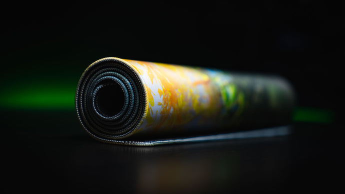 Rolled deskmat edge-on, showing the stitched border and the cushioned 4 mm core