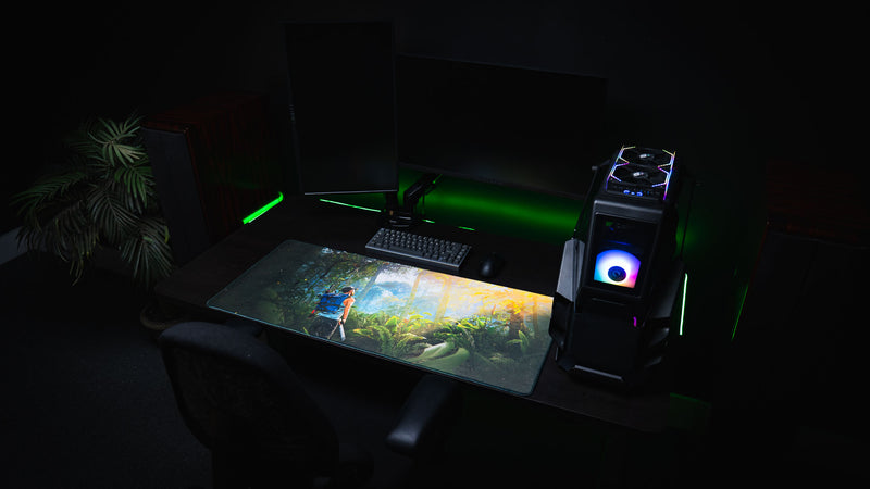 Wide gaming desk setup featuring the Jungle Exploration deskmat with a Rust survivor exploring a lush tropical jungle beneath golden sunlight.