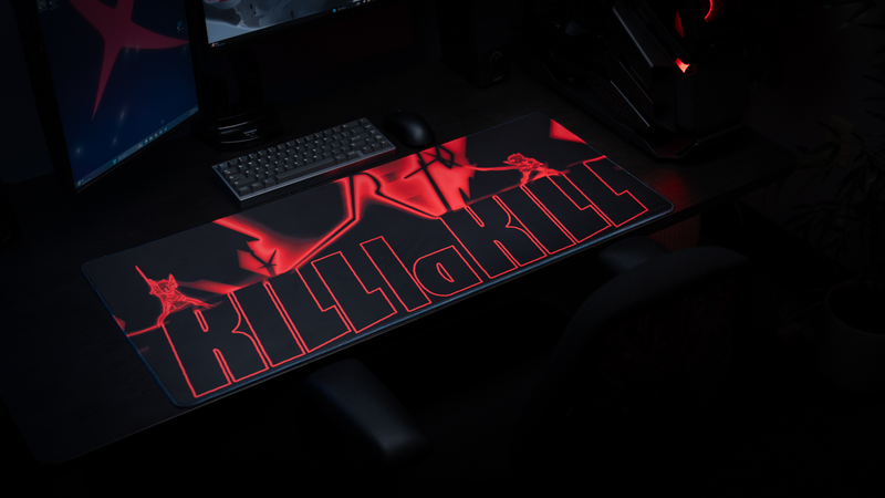Anime battlestation setup featuring the Kill la Kill “Kamui Clash” deskmat with glowing red combat artwork, keyboard, and gaming PC.