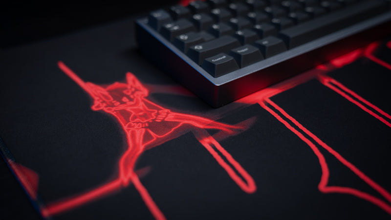 Close-up of the Kill la Kill “Kamui Clash” anime deskmat featuring glowing red character artwork beneath a mechanical keyboard.