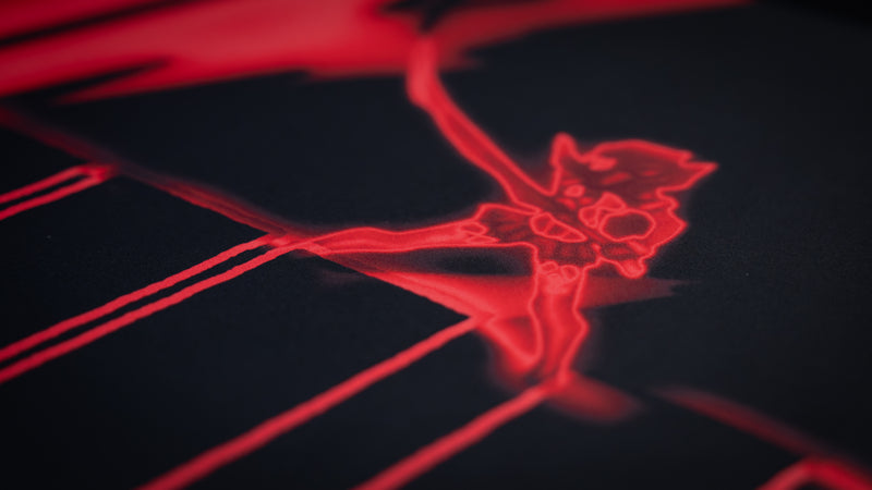 Close-up of the Kill la Kill “Kamui Clash” anime deskmat featuring glowing red neon character artwork on a dark premium fabric surface
