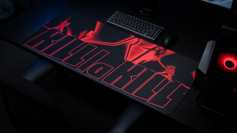 Premium gaming setup featuring the Kill la Kill “Kamui Clash” deskmat with glowing red anime battle artwork, keyboard, and gaming PC.