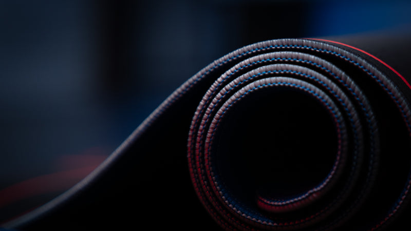 Macro close-up of the rolled Kill la Kill “Kamui Clash” deskmat highlighting premium stitched edges and layered fabric construction.