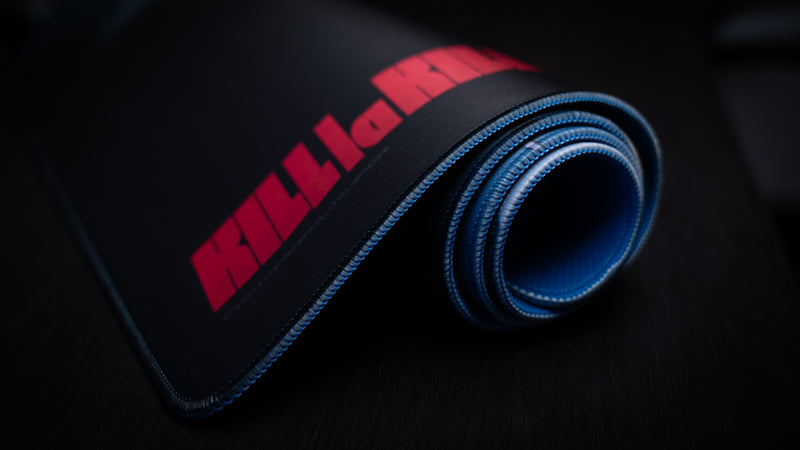 Rolled Kill la Kill “Scissorblade” anime deskmat showcasing stitched edges, smooth fabric surface, and bold red logo detailing.