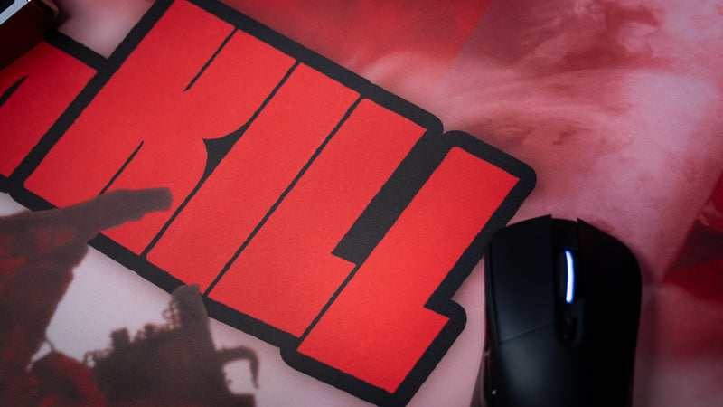 Close-up of the Kill la Kill “The First Duel” anime gaming deskmat showcasing vivid red typography, smooth surface texture, and a gaming mouse.