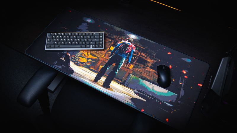 Angled view of the Last Man Standing official Rust gaming deskmat featuring a lone survivor inside a dimly lit base with a keyboard and mouse on a gaming setup.