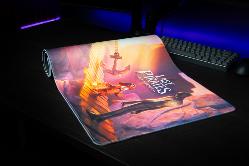 Partly rolled Last Pirates Bridge Escape desk mat on a gaming desk beside a keyboard