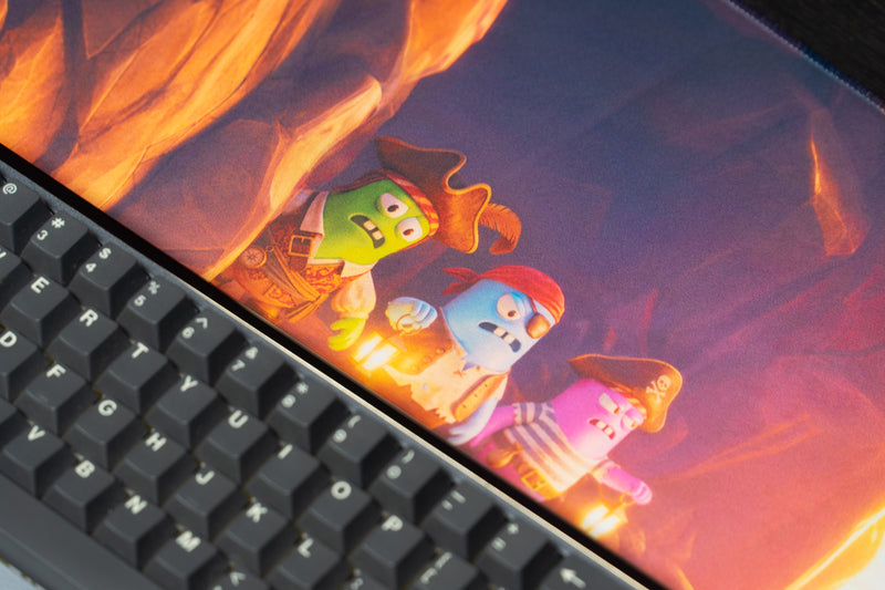 Close-up of three colorful Last Pirates crewmates on the Bridge Escape desk mat beside a keyboard