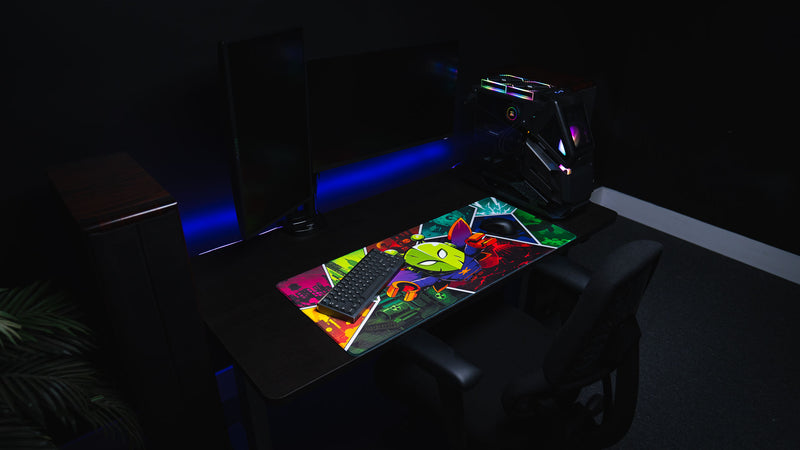 Wide gaming desk setup featuring the Lure of the Night deskmat with a colorful comic-style moth character and Rust-inspired biome artwork.