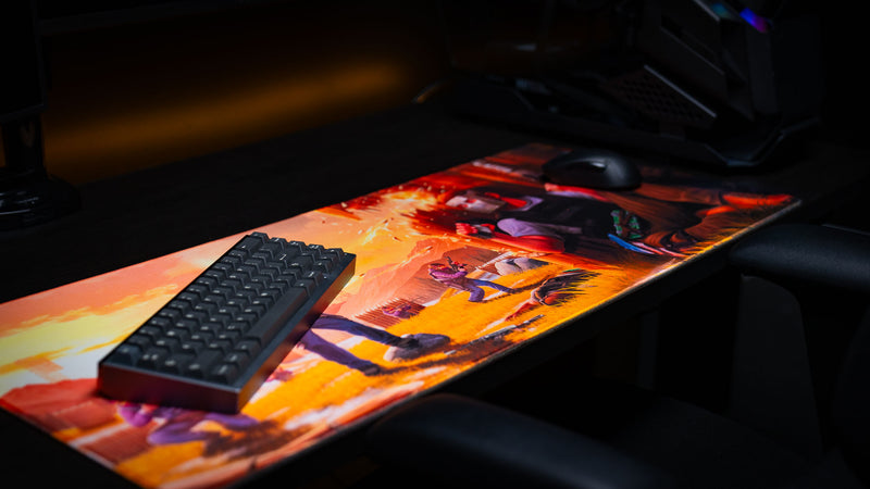 Angled gaming setup featuring the main scene Rust deskmat beneath a compact mechanical keyboard and gaming mouse, highlighting the expansive artwork, vibrant colors, stitched edges, and premium gaming surface.