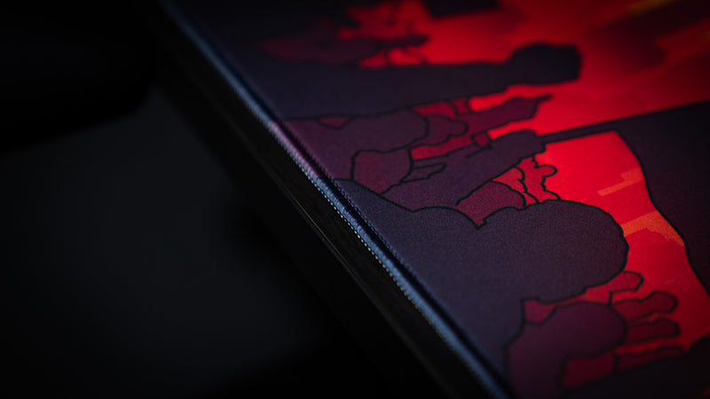 Close-up of the stitched edge and crowd silhouettes on the MapleTakes Golden Hour Defiance gaming deskmat