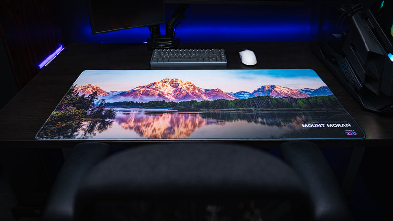 Mount Moran deskmat displayed in a premium gaming setup, featuring Grand Teton National Park, mirror-like lake reflections, vivid HD photography, and stitched edges.