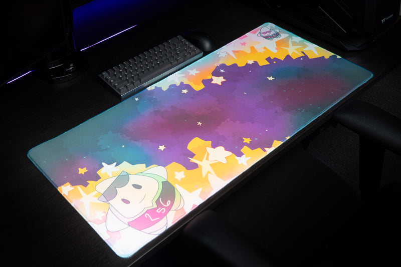 Angled workstation view of the MVP Galaxy desk mat showing its teal-purple galaxy and star border.