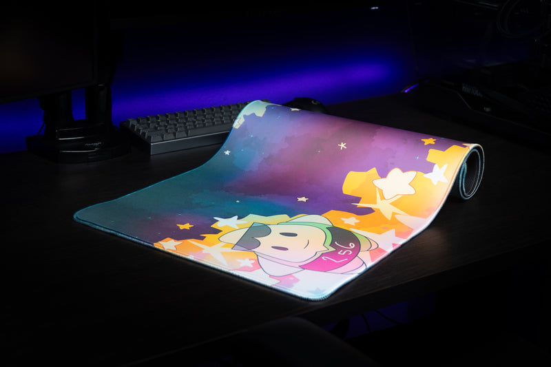 MVP Galaxy desk mat partially rolled on a dark desk, showing the 256 mascot and colorful stars.