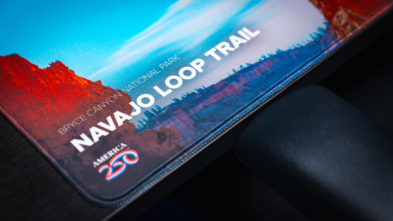Close-up of the Navajo Loop Trail deskmat highlighting Bryce Canyon National Park branding, the America 250 logo, premium stitched edges, and crisp HD print quality.