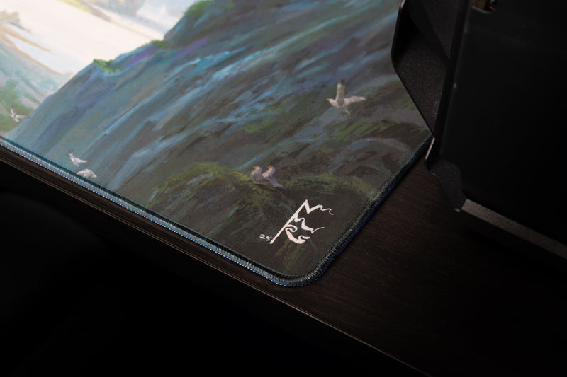 Close-up of the Lake of Laugg deskmat corner showing Nick Ragetli's signature and stitched border