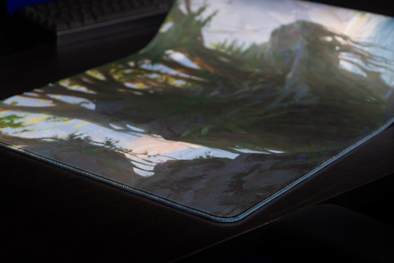 Close-up of the Lake of Laugg deskmat's forest artwork and stitched corner
