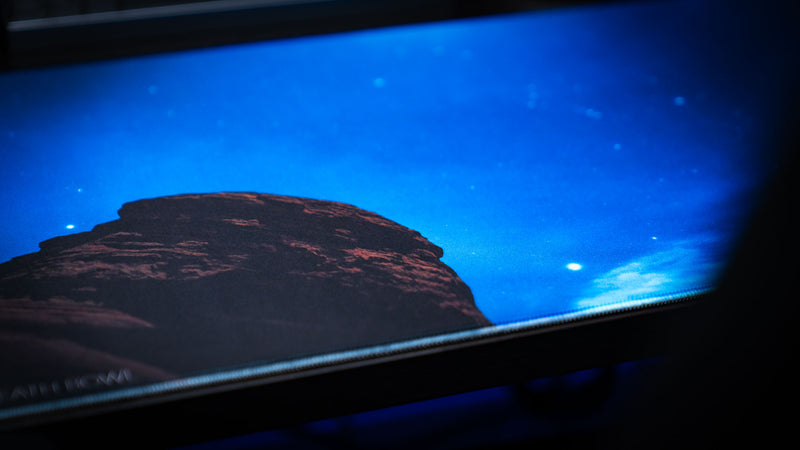 Macro close-up of the Nightsky Death Bowl deskmat highlighting the silhouetted sandstone formation against a brilliant star-filled night sky with premium stitched-edge detailing.