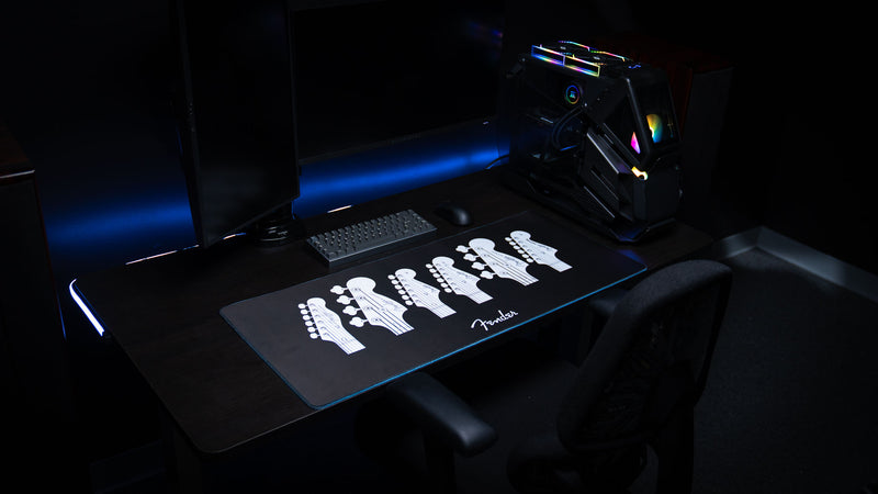 Full-width view of the Fender Headstocks XXL desk mat with white instrument line art on black