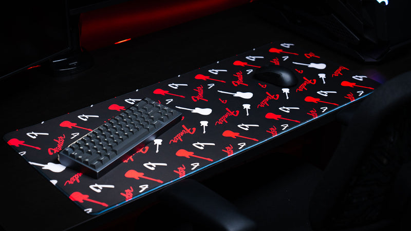 Full-width desk view of the Fender Repeat desk mat with continuous red branding