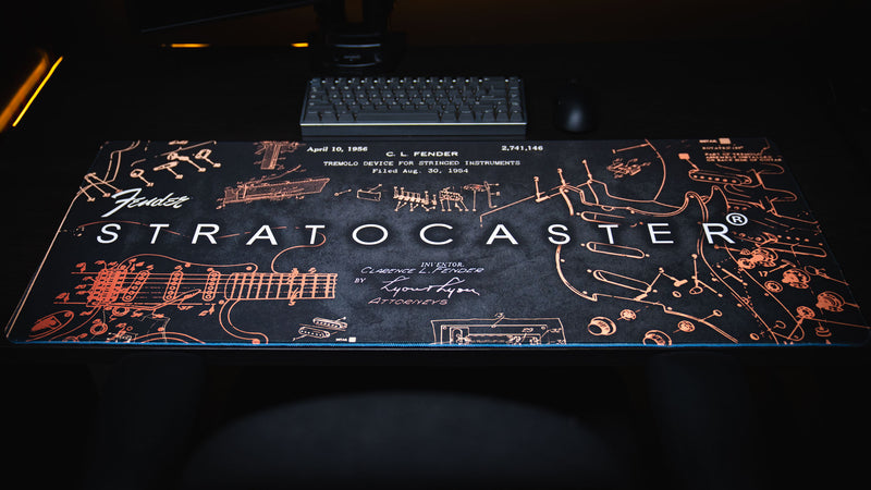 Close view highlighting copper Stratocaster callouts across the deep black desk mat