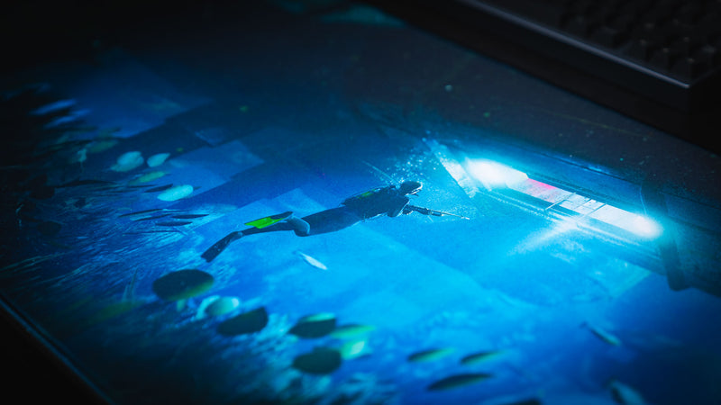 Close-up of the Official Rust Labs Breach deskmat featuring a diver swimming beneath the Labs monument with vibrant underwater lighting, marine life, and premium HD print quality.