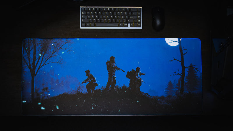 Official Rust Twilight Roam deskmat shown from above, featuring three survivors silhouetted beneath a full moon in a dark forest with glowing blue night lighting.
