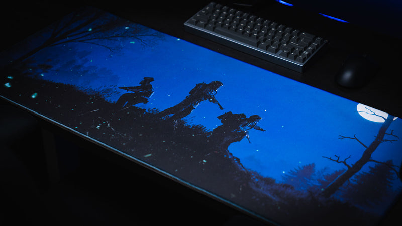 Official Rust Twilight Roam deskmat featuring three hazmat survivors silhouetted beneath a bright moon with a mechanical keyboard and gaming mouse.