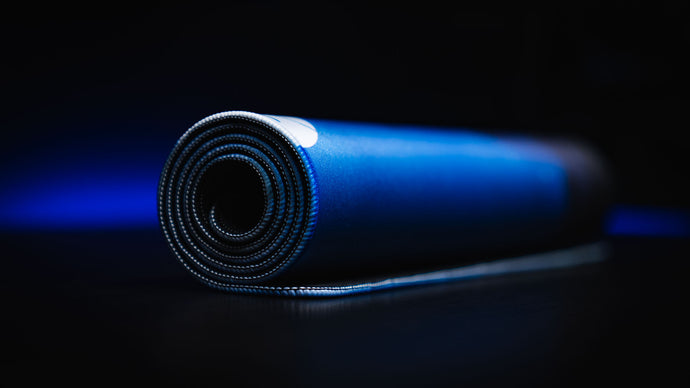 Rolled deskmat edge-on, showing the stitched border and the cushioned 4 mm core