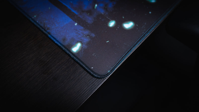 Close-up of the stitched edge on the Official Rust Twilight Roam deskmat, highlighting the premium fabric, reinforced stitching, and moonlit blue artwork.
