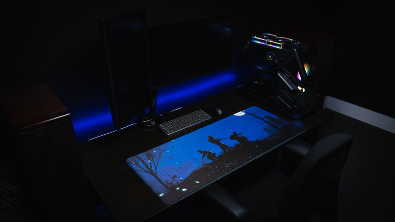 Official Rust twilight Roam deskmat displayed in a complete gaming room setup with dual monitors, RGB gaming PC, mechanical keyboard, and mouse.