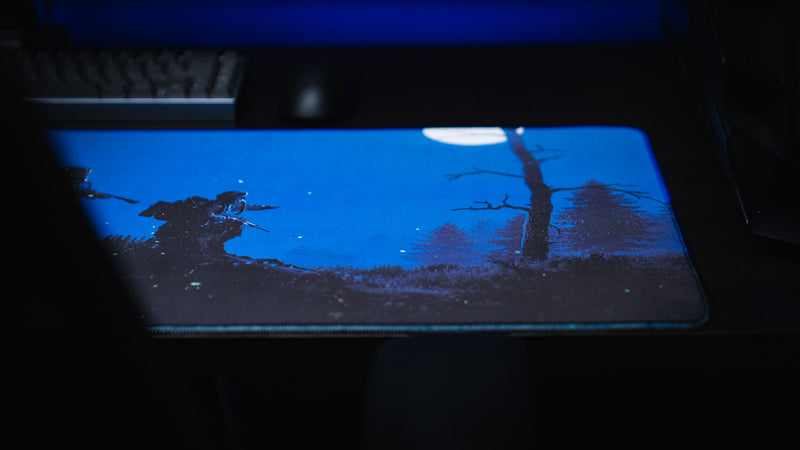 Angled view of the Official Rust twilight Roam deskmat featuring hazmat survivors moving through a moonlit forest landscape with stitched edges.