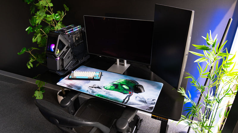 Oilrats Frozen Paradise deskmat displayed in a gaming setup with keyboard and mouse, featuring a frozen landscape, giant green skull monument, and icy reflections inspired by Rust.