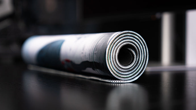 Rolled deskmat edge-on, showing the stitched border and the cushioned 4 mm core
