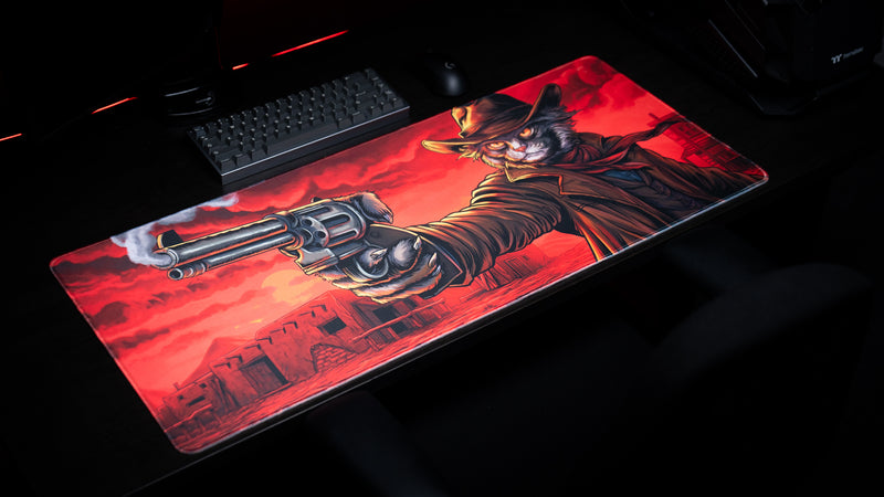 Angled view of Only PVP Cat deskmat on a dark gaming desk, with a smoking revolver and cowboy cat across a red sky.