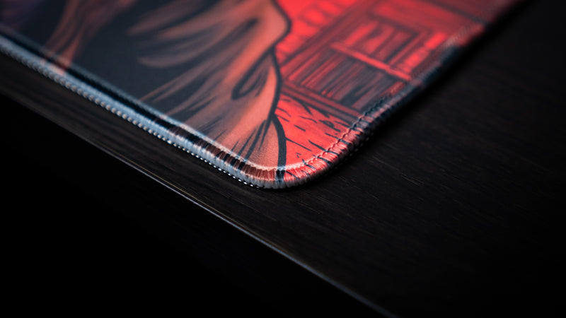Close-up of the stitched corner on Only PVP Cat deskmat, with red Western artwork printed up to the border.