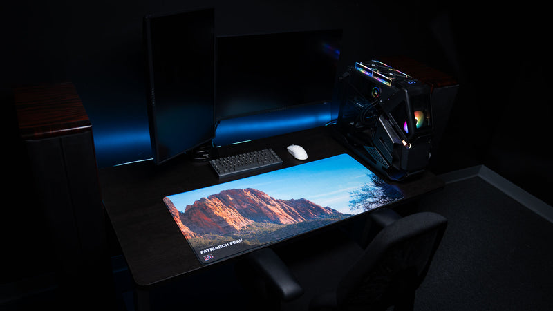 Patriarch Peak deskmat displayed in a modern gaming desk setup, showcasing Zion National Park's towering sandstone cliffs with vibrant HD photography and premium stitched edges.