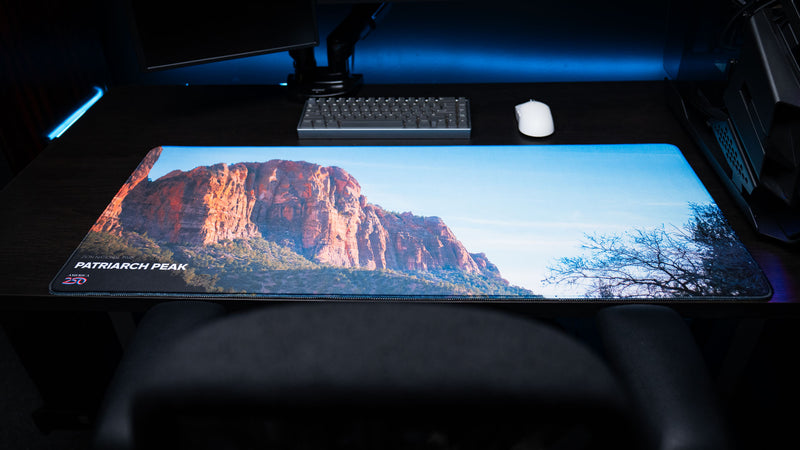 Wide view of the Patriarch Peak deskmat featuring Zion National Park's towering sandstone cliffs, premium stitched edges, vibrant HD photography, and a modern gaming setup.