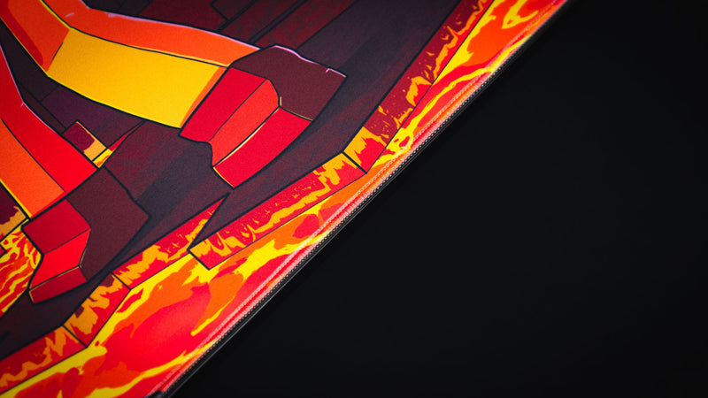 Close-up of the PhoenixSC deskmat artwork showing the lava-bright border and blocky character legs