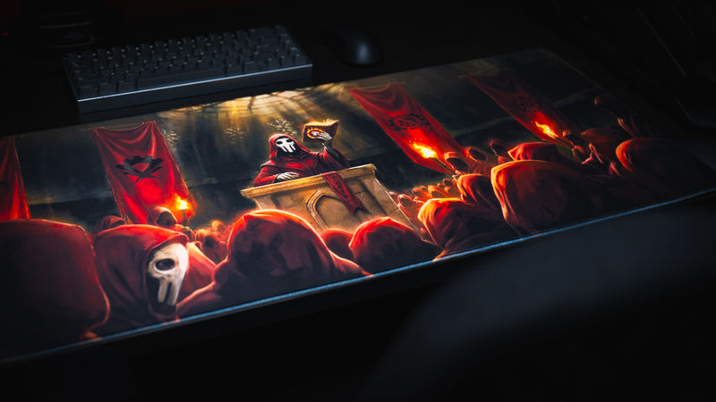 Angled view of the Pravus Crimson Convocation deskmat featuring a masked cult leader, crimson-robed followers, blazing torches, and cathedral banners in a dark fantasy scene.