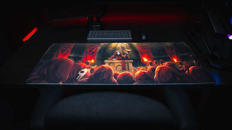 Front view of the Pravus Crimson Convocation deskmat displayed across a gaming desk, featuring a masked cult leader, crimson-robed followers, and glowing torchlit cathedral artwork.