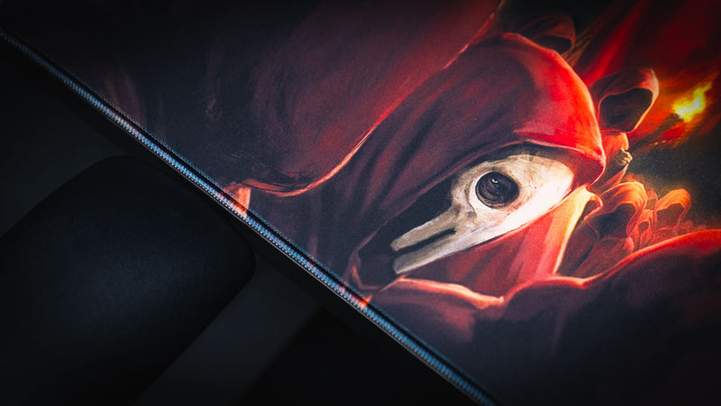 Close-up of the Pravus Crimson Convocation deskmat featuring a crimson-robed follower wearing a plague mask with dramatic torchlit fantasy artwork and premium stitched edges.